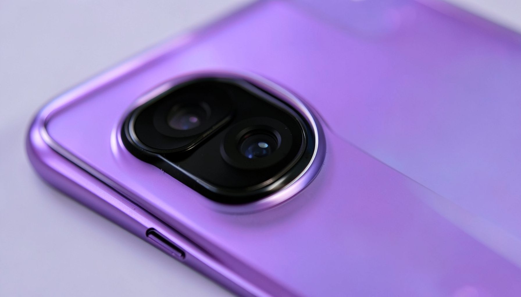 Close-up of a smartphone camera lens module with metallic rings and a glossy back panel in gradient purple