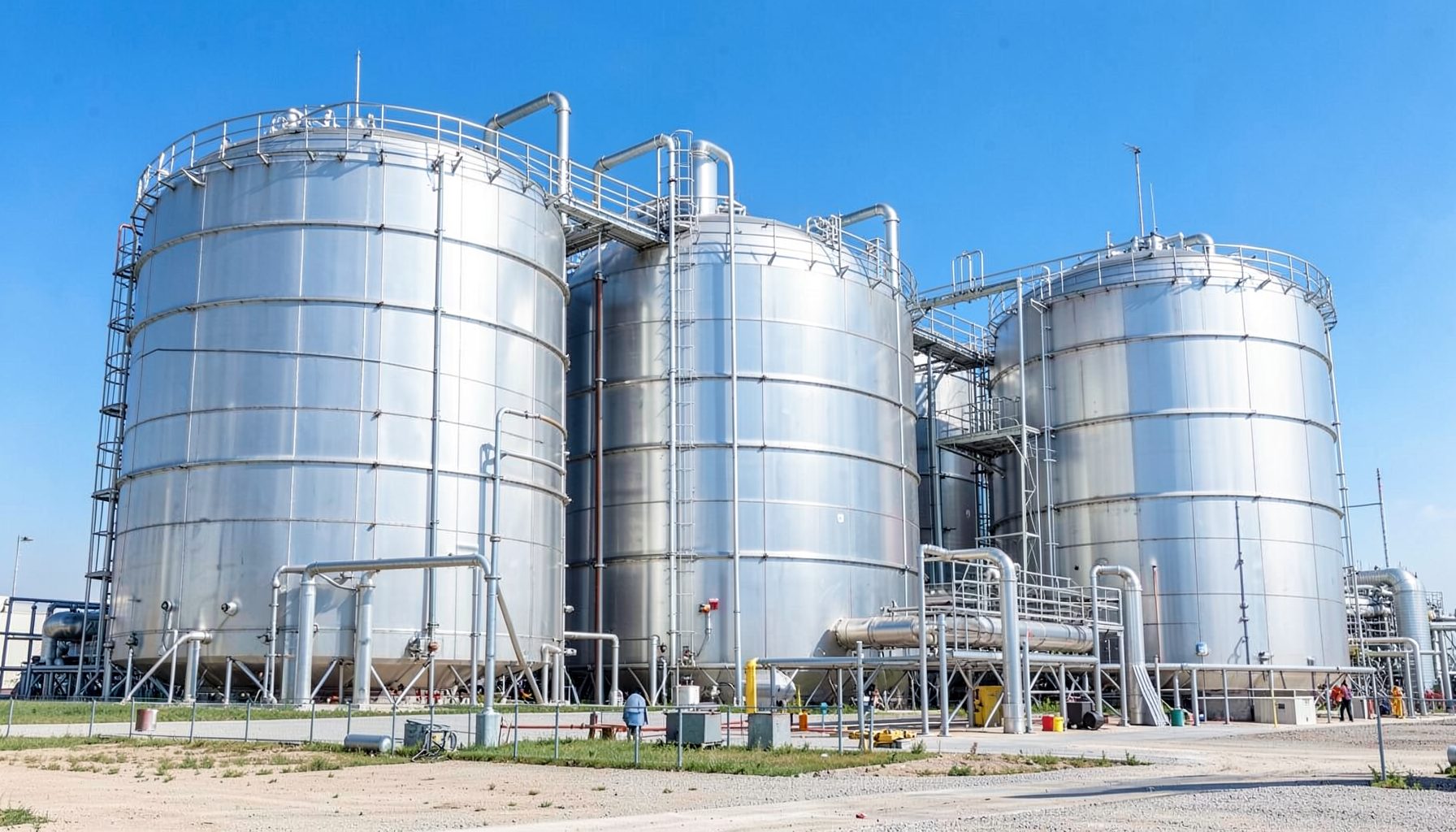 Industrial hydrogen facility with large metallic storage tanks under a bright blue sky